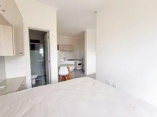 Quarto com cama grande e vista para uma área de cozinha moderna.