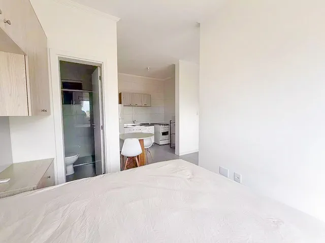 Quarto com cama grande e vista para uma área de cozinha moderna.