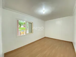 Foto de um cômodo interno com paredes brancas e piso de madeira.