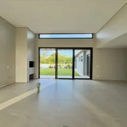 Ambiente interno amplo com portas de vidro que dão acesso a um jardim.