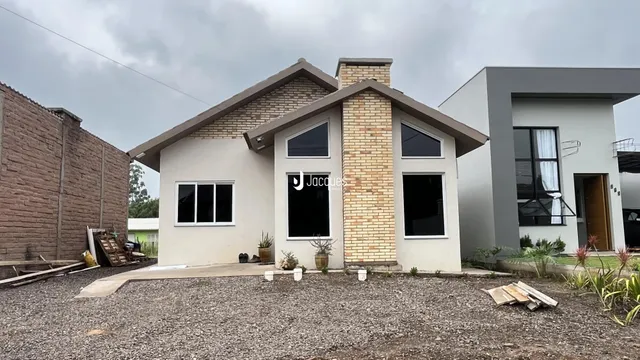 Fachada de uma casa em Lajeado, Brasil, com acabamento em tijolo aparente e reboco branco.