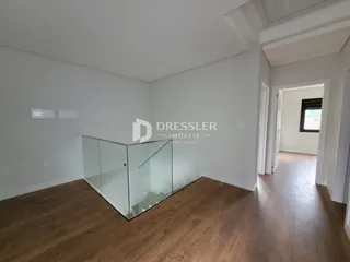 Vista interna de um ambiente com piso de madeira e divisória de vidro.