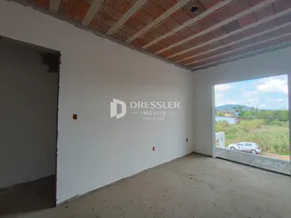 Vista interna de uma sala com teto de tijolos expostos e paredes brancas.