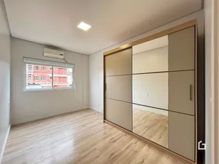 Sala de estar com piso de madeira clara e janela.