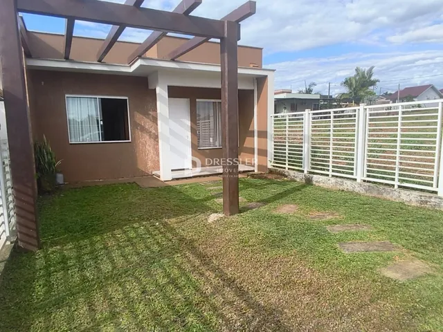 Foto da fachada de uma residência em Lajeado, Brasil, com jardim frontal e cerca branca.
