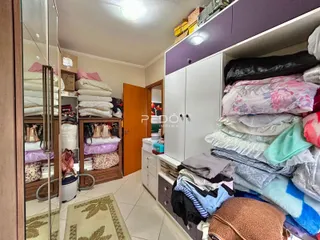 Quarto com armário e roupas espalhadas.