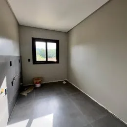 Foto de um cômodo interno com parede clara e janela.