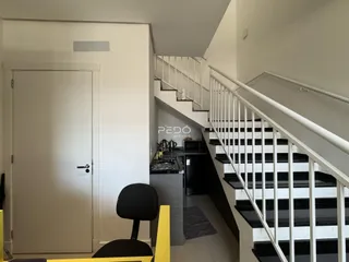 Hall de entrada com escadaria e vista para a cozinha de um imóvel em Lajeado.