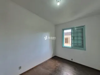 Imagem de uma sala de estar com piso de madeira e parede branca.