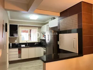 Foto de uma cozinha moderna com armários brancos e bancadas escuras.