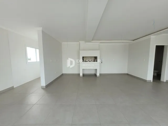 Foto de uma sala de estar ampla com paredes brancas e piso claro.