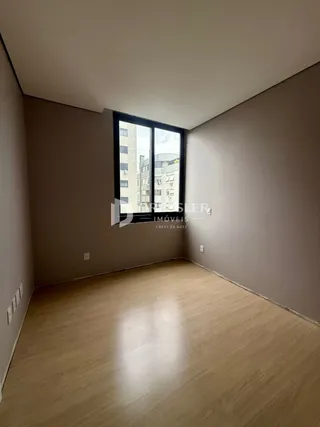 Ambiente interno de uma sala com piso de madeira e janela.