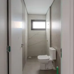 Foto de um corredor interno mostrando um vaso sanitário branco.