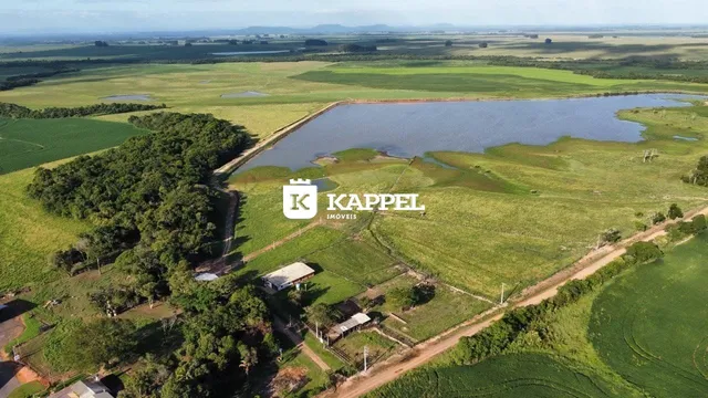 Vista aérea de uma propriedade rural com campos verdes e um lago.