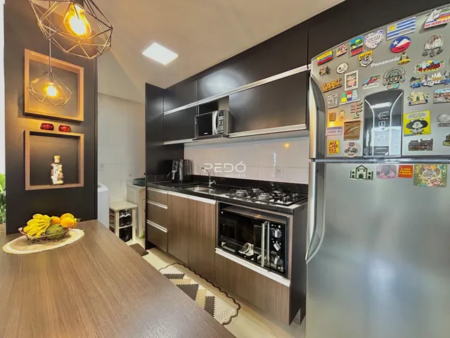 Vista da cozinha moderna com armários escuros e eletrodomésticos de aço inoxidável.