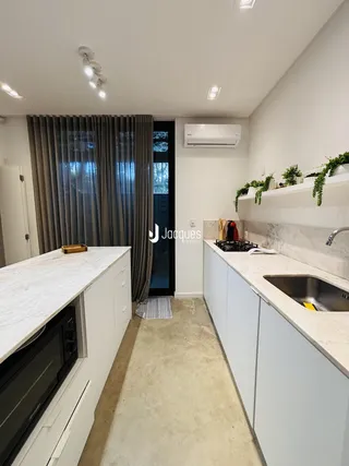 Cozinha moderna com armários brancos e bancadas de mármore claro.