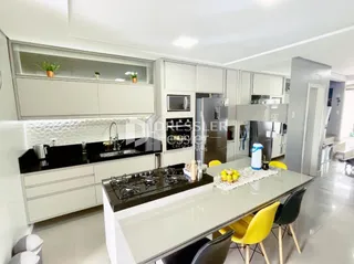 Uma cozinha moderna com armários brancos e bancadas escuras.