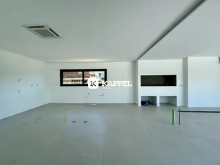 Ambiente interno amplo e vazio com piso de concreto e ar-condicionado instalado.