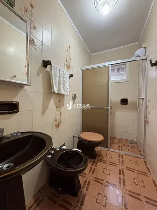 Banheiro com revestimento cerâmico e piso de terracota.