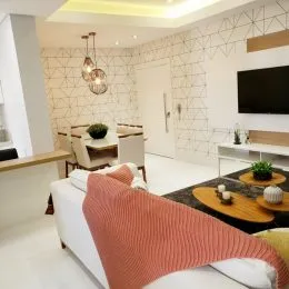 Uma sala de estar moderna com sofá branco e televisão na parede.