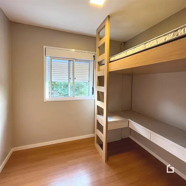 Quarto com piso de madeira e estrutura de cama alta.