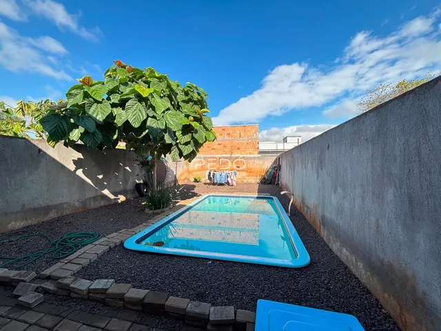 Piscina externa em área de lazer com muro de contenção.