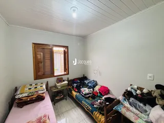 Quarto com duas camas e janela de madeira na sala.