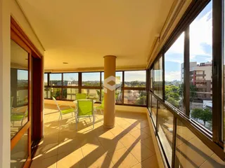 Vista de uma varanda com móveis ao lado de grandes janelas.