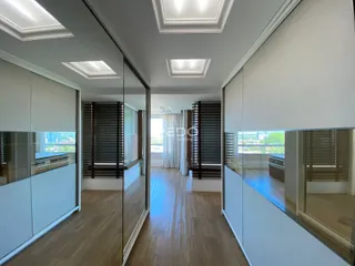 Hall de entrada com piso de madeira clara e divisórias de vidro.