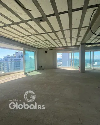 Espaço interno com teto de concreto e grandes janelas de vidro.
