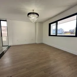 Sala de estar com piso de madeira e lustre no teto.