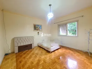 Quarto com piso de madeira clara e janela.