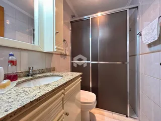 Interior de um banheiro com bancada e porta de vidro.