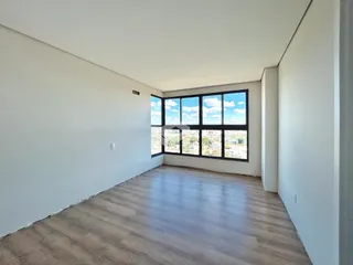 Ambiente interno de um imóvel com paredes brancas e grande janela.