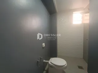 Foto de um banheiro interno com parede cinza e janela.