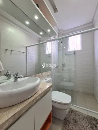 Foto de um banheiro com azulejos brancos e box de vidro.