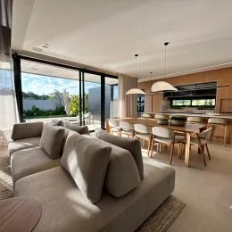 Sala de estar com sofá grande e portas de vidro que dão para o exterior.