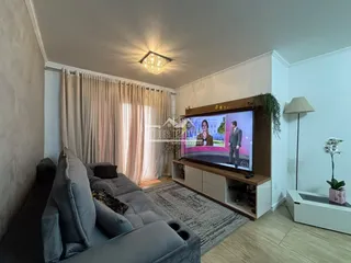Sala de estar com sofá e televisão em um apartamento.