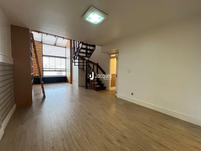 Ambiente interno com piso de madeira e escadaria em uma sala de estar.