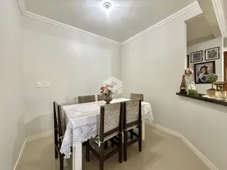 Uma sala de jantar com mesa posta e cadeiras de madeira.