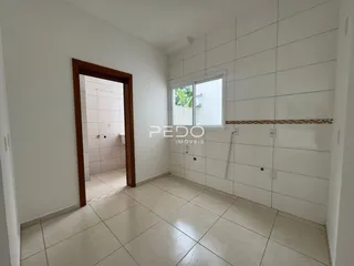 Interior de um corredor com paredes brancas e piso de cerâmica.