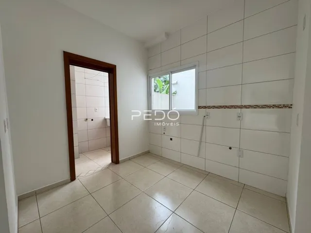 Interior de um corredor com paredes brancas e piso de cerâmica.