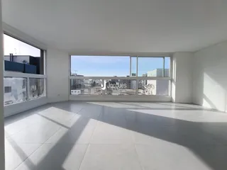 Sala ampla com piso de cerâmica e grandes janelas que dão vista para a cidade.