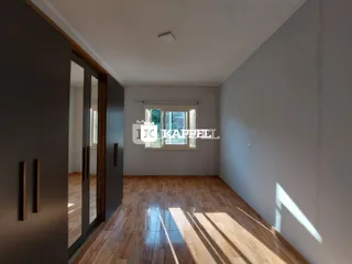 Hall de entrada com piso de madeira e janela iluminada.