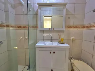 Banheiro com revestimento cerâmico e box de vidro.