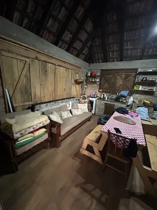 A sala apresenta um teto abobadado de madeira e um sofá.