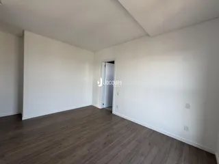 Um cômodo interno com piso de madeira e paredes brancas.