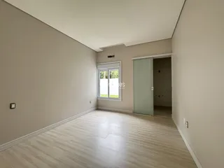 Interior de uma sala com piso de madeira clara e paredes neutras.