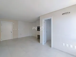 Vista interna de um espaço amplo com paredes brancas e piso claro.