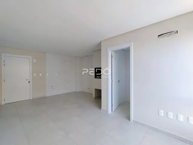 Vista interna de um espaço amplo com paredes brancas e piso claro.